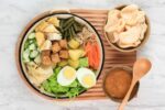 Gado-gado adalah hidangan Indonesia dengan sayuran, tahu, tempe, telur, dan saus kacang.